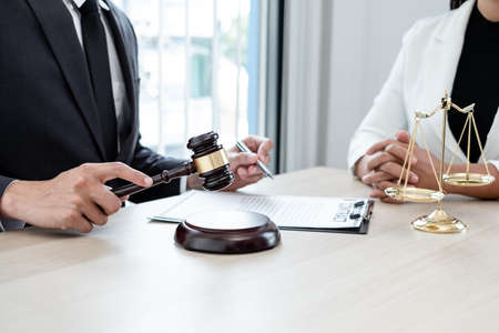 A male lawyer or a judge counseling clients about judicial justice and prosecution with scales, judges gavel, legal documents legal services concept.の写真素材