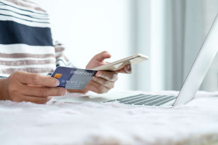 The businesswoman's hand is holding a credit card and using a smartphone for online shopping and internet payment in the office.の写真素材