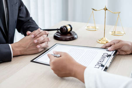 A male lawyer or a judge counseling clients about judicial justice and prosecution with scales, judges gavel, legal documents legal services concept.の写真素材