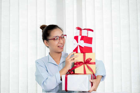 Asian woman holding a gift box Glad to be the giver of surprise with excitement, joy, and smiles on...