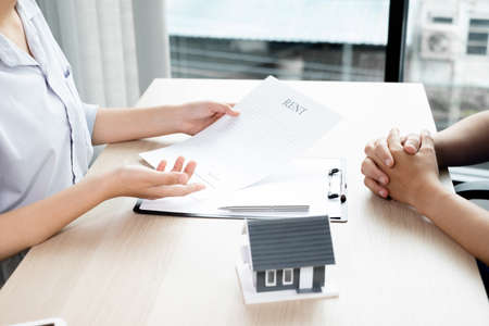 A real estate agent with a home model is talking to clients about renting a home and buying home insurance. Home rental and insurance concept.の写真素材