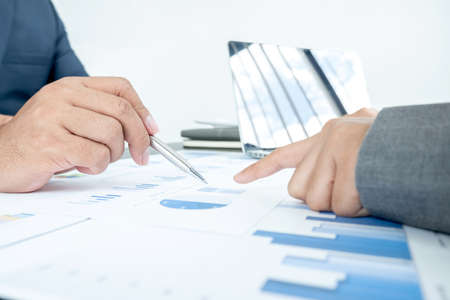Two business leaders talk about charts, financial graphs showing results are analyzing and...