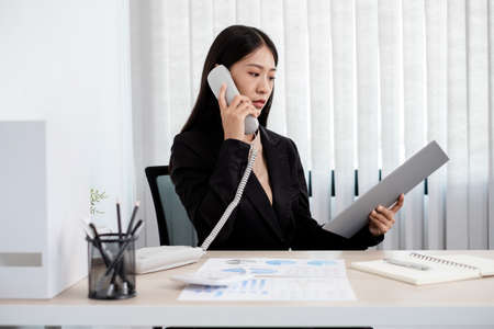 Asian businesswoman talking on the phone and working with a cheerful and happy smile while working at the office.の写真素材