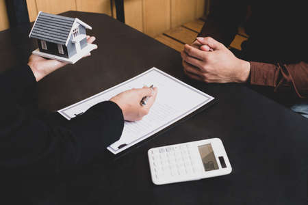A real estate agent with a House model is talking to clients about buying home insurance. Home insurance concept.の写真素材