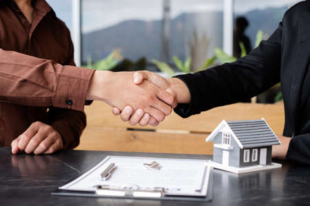 Businessmen and brokers real estate agents shake hands after completing negotiations to buy houses insurance and sign contracts. Home insurance concept.の写真素材