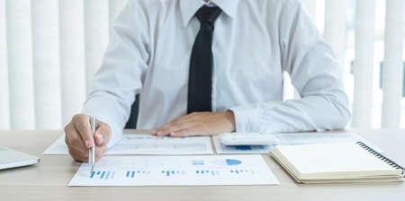 The businessman hand sits at their desks and calculates financial graphs showing the results of...