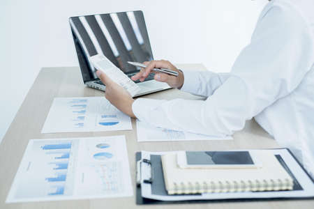 The businessman hand sits at their desks and calculates financial graphs showing the results of...