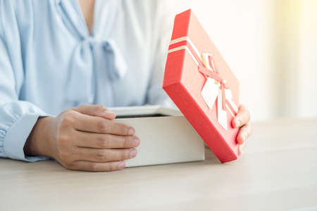 A hand opens a surprise box with excitement and joy in the holidays, Christmas, birthdays, or Valentine's Day.の写真素材