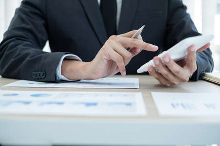 The businessman hand sits at their desks and calculates financial graphs showing the results of...