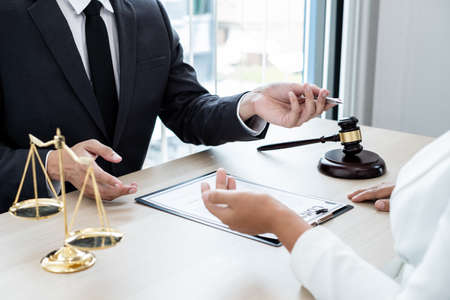 A male lawyer or a judge counseling clients about judicial justice and prosecution with scales, judges gavel, legal documents legal services concept.の写真素材