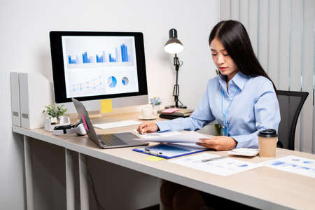 Asian women sit at their desks and calculate financial graphs showing results about their investments, plan a successful business growth process.の写真素材