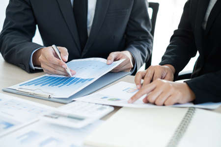 Two business leaders talk about charts, financial graphs showing results are analyzing and...