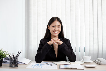 Asian businesswomen sit at their desks and calculate financial graphs showing results about their investments, plan a successful business growth process in the office.の写真素材