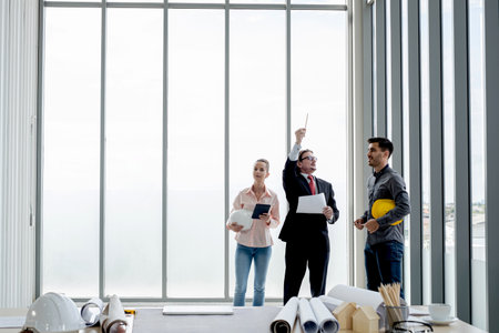 Team of male and female engineers and architects, working team, meeting, discussing construction and drawing construction plans, printing, writing on-site construction sites.の写真素材