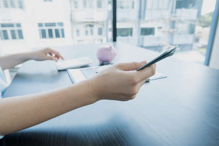 Women's hands hold a dollar and using a calculator Calculate graphs to build successful and economical businesses for retirement concepts.の写真素材