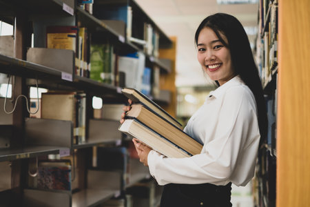Young Asian women are searching for books and reading books on the tables and aisles of the college...