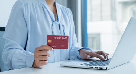 The businesswoman's hand is holding a credit card and using a laptop for online shopping and internet payment.の写真素材