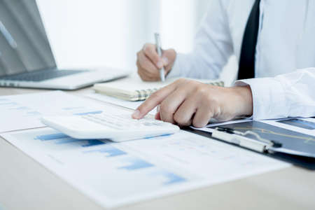 The businessman hand sits at their desks and calculates financial graphs showing the results of their investments planning the process of successful business growth.