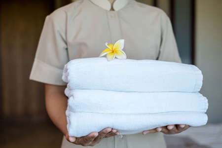 A hotel maid holds towels and places flowers in a hotel room.の写真素材