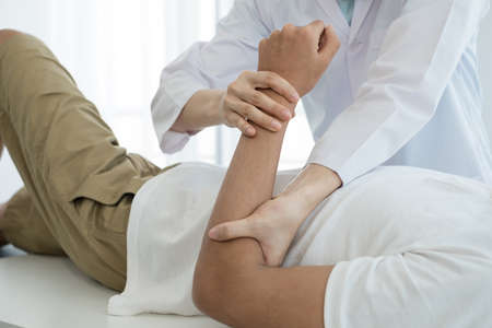 Female physiotherapists provide assistance to male patients with elbow injuries examine patients in rehabilitation centers. Physiotherapy concepts.の写真素材