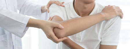 Female physiotherapists provide assistance to male patients with elbow injuries examine patients in rehabilitation centers. Rehabilitation physiotherapy concept.の写真素材