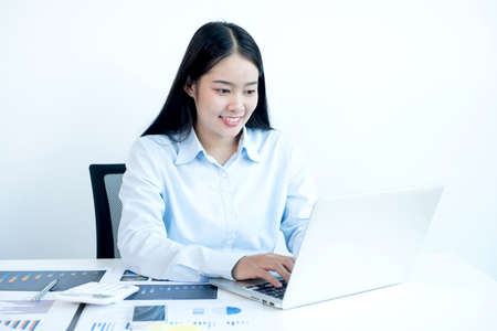 Asian female accountant sits at their desks and calculates financial graphs showing results about their investments, plan a successful business growth process.の写真素材