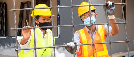 A team of male and female engineers or architects is exploring and inspecting the outdoor construction site work.の写真素材