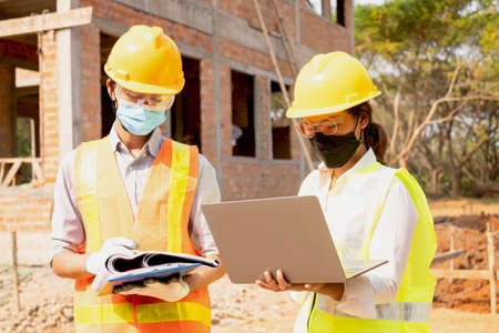 A team of male and female engineers or architects is exploring and inspecting the outdoor...