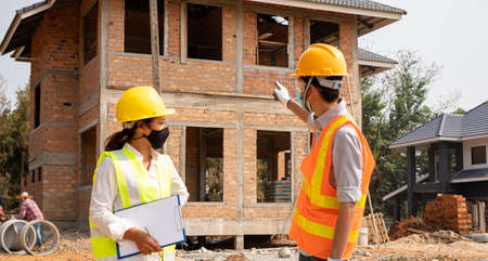 A team of male and female engineers or architects is exploring and inspecting the outdoor...