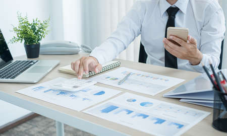 The businessman hand sits at their desks and calculates financial graphs showing the results of their investments planning the process of successful business growth.の写真素材
