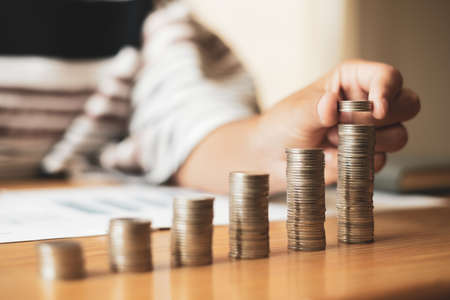 Woman's hand. Place a coin on the coin graph with coins, saving money with coins, stepping into a...