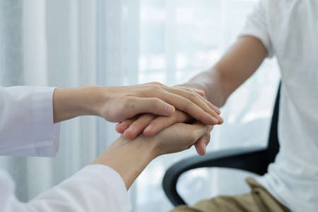 The female doctor uses a friendly hand to hold the patient's hand to give confidence and show care about health care. Medical concepts and good health.の写真素材