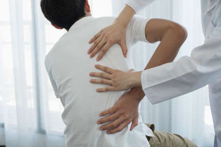 Female physiotherapists provide physical assistance to male patients with back injuries back...