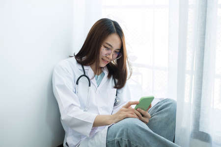 Female doctors Sitting Sit play phone enjoy the pleasure of using a smartphone device during their...