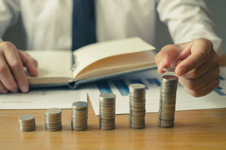 Man's hand. Place a coin on the coin graph with coins, saving money with coins, stepping into a successful growing business, and saving for thought in retirement. Retirement savings concept.の写真素材