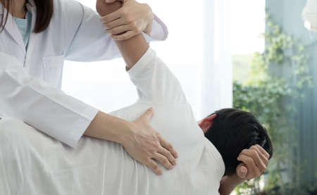 Female physiotherapists provide physical assistance to male patients with back injuries back...
