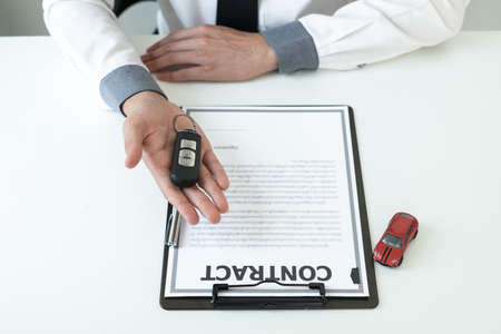 Car dealer businessman holding a car key. Car loan and insurance concept.