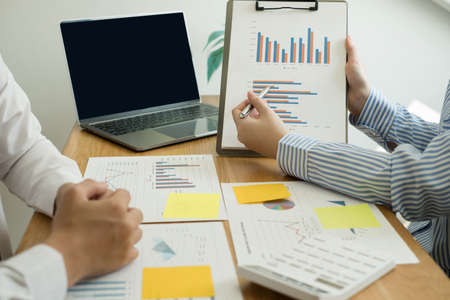 Two business leaders talk about charts, financial graphs showing results are analyzing and...