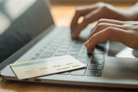 The businesswoman's hand is holding a credit card and using a laptop for online shopping and...