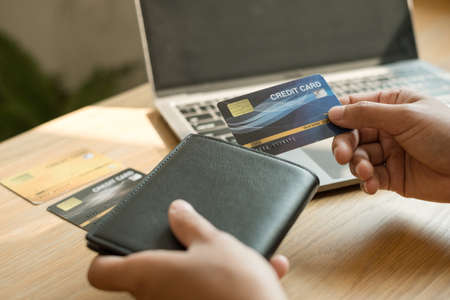 The businesswoman's hand is holding a credit card and using a laptop for online shopping and internet payment.の写真素材
