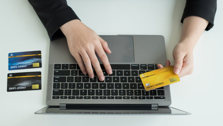 The businesswomen's hand is holding a credit card and using a laptop for online shopping and...
