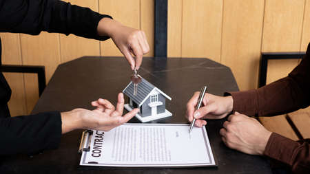 A real estate agent broker hand over the house key to the new owner after completing the signing...