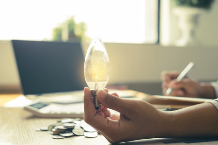 Hand of a businesswoman's hand Innovative and inspired by light bulbs and coins, Calculating...
