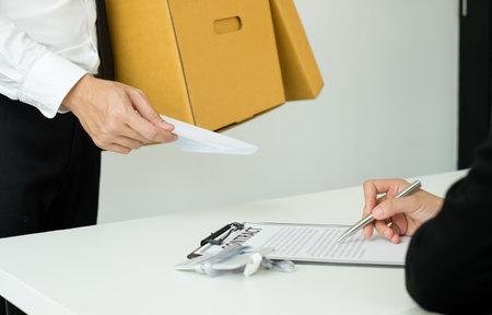Desperately fired man office worker employee hands her employer her resignation letter and packs her...