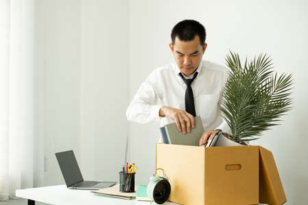 A male office worker is unhappy with being fired from a company packing things into cardboard boxes....