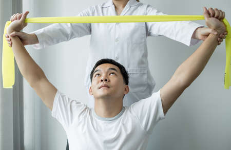 Female physiotherapists are helping male patients with arm injuries, arms pulling, muscle relaxation...