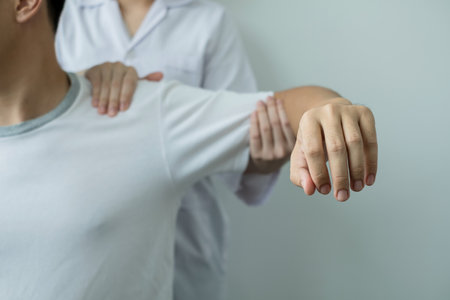 Female physiotherapists provide assistance to male patients with elbow injuries examine patients in rehabilitation centers. Physiotherapy concepts.の写真素材