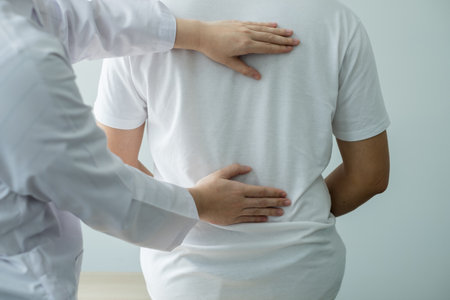 Female physiotherapists provide physical assistance to male patients with back injuries back...