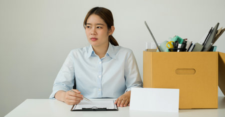 A woman office worker, dissatisfied with the termination, packs her belongings in a cardboard box...