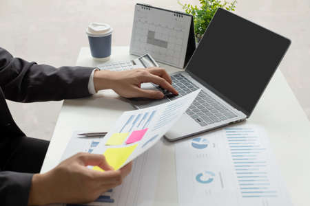 The businessman hand sits at their desks and calculates financial graphs showing the results of...